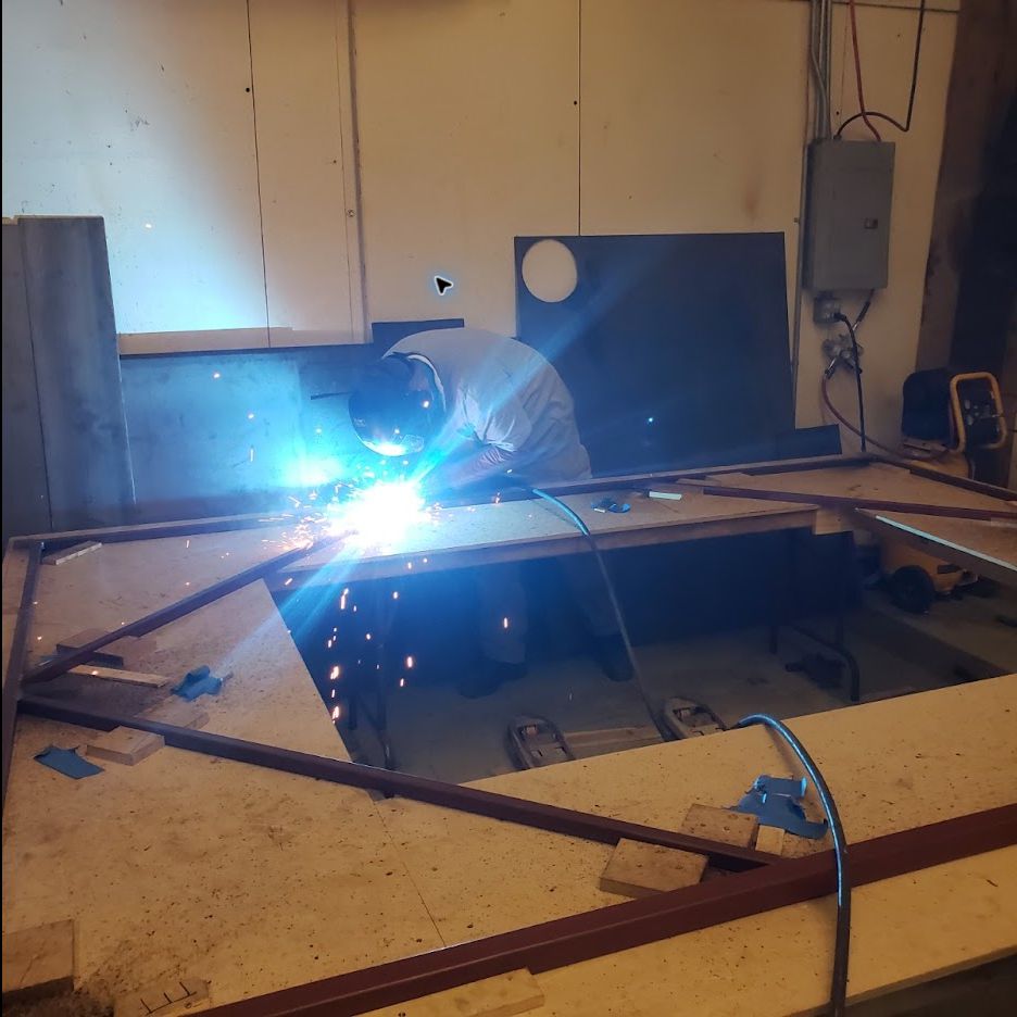 Chris Halladay welding a large steel frame on a shop jig